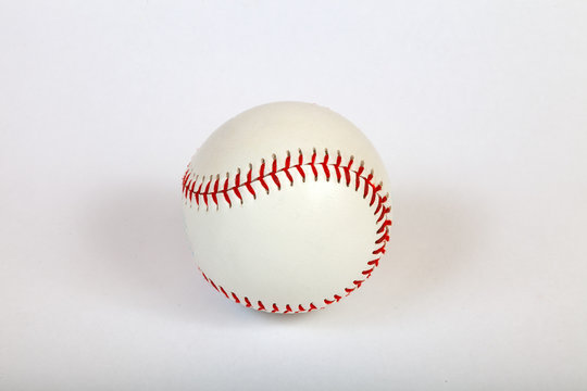 Close-up on a white baseball ball stitched with red thick thread made of genuine leather for the American team game on a white isolated background
