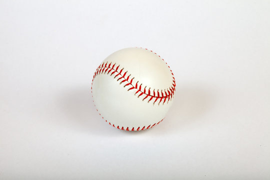 Close-up on a white baseball ball stitched with red thick thread made of genuine leather for the American team game on a white isolated background