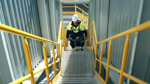 Team of male factory workers wearing protective uniform going up on stairs