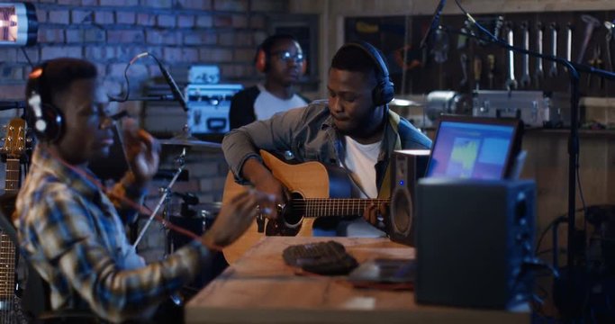 Medium long shot of young male musicians recording music in home studio