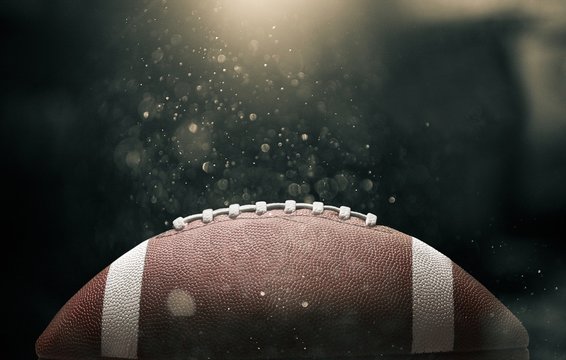American football ball on black background illuminated by the
