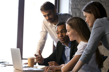 Smiling diverse office workers using laptop discussing online project or making conference video...