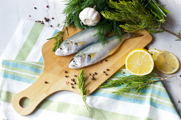 Fresh fish with the vegetables, condiment and lemon, bluefish. Food preparation.
