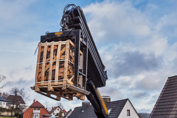 Eine Palette Kaminholz schwebt in der Luft an einem Kran