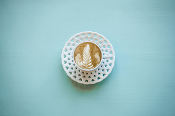 A cup with a traditional tasty and aromatic morning cappuccino on a blue background.