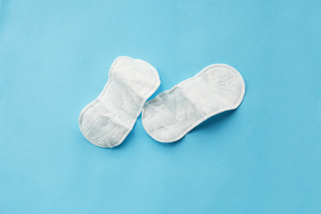 a pair of crumpled cotton menstruation pads lying on light blue background, women critical days problems.