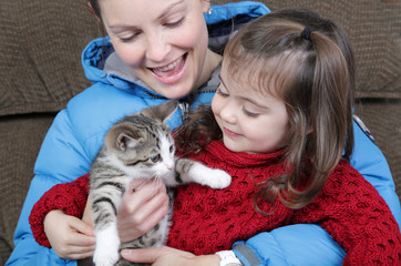 Fototapeta na wymiar child looking kitten with her mother
