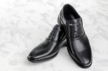 Men's shoes made of black leather on a light background. Comfortable shoes of a successful businessman. Fashionable and elegant accessories in daily life. New, modern, classic high heel shoes.
