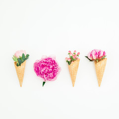 Floral concept of pink peonies, roses petals and waffle cones on white background. Flat lay, top view