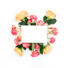 Paper envelope with red and orange roses and leaves on white background. Flat lay, top view. Beauty concept