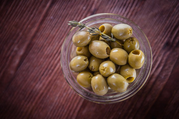 Olives in oil in a glass bowl on a wooden table