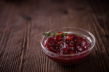 Cowberry sauce in a glass bowl on a wooden table