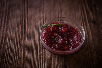 Cowberry sauce in a glass bowl on a wooden table