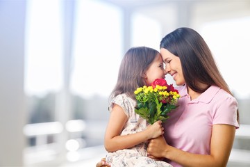 Fototapeta na wymiar Portrait of happy mother and daughter holding flowers