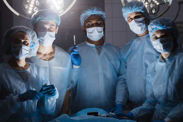Hospital concept. Surgery team looking at camera in the operating room in a hospital clinic while operating on a patient in emergency case