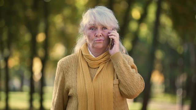 Sad Senior Lady Talking On Mobile Phone In Park, Lonely, No Family And Friends