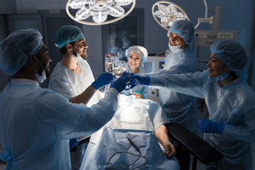 Cheerful team of surgeons congratulating each other with New Year, cheering with glasses of non alcoholic lemonade. Doctor s occupation goes without holidays if it is your working shift.