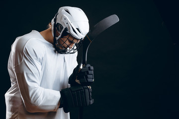 Isolated studio shot of serious concentrated hockey player with hockey stick prepares alone for...