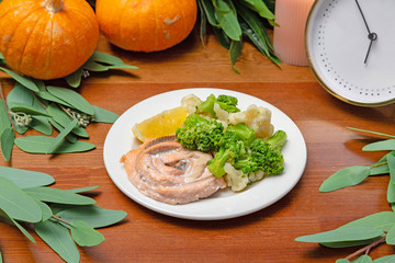 Fish with vegetables in a plate on the table
