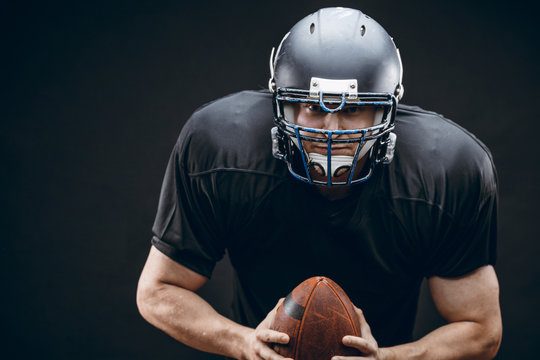 Sport concept. American football sportsman player in black sports outfit on black background with copy space. Sport concept.