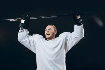 Naklejka premium Portrait of cheerful handsome hockey player getting into the mood for winning before game starts. Sportsman in white uniform celebrating the victory. Sport, Achievements and People concept