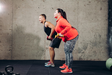 full length side view photo. plump woman with personal trainer . exercise program helping you gain...