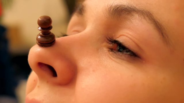 macro small chess piece black pawn stands on nose tip of beautiful girl lying motionless in daylight