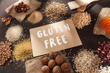 Gluten free flour and cereals millet, quinoa, corn bread, brown buckwheat, rice, bread and pasta with text gluten free in English language with spoon on wooden background, top view - obrazy, fototapety, plakaty