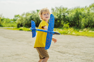 Happy kid playing with toy airplane against old runway background. Traveling with kids concept