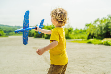 Happy kid playing with toy airplane against old runway background. Traveling with kids concept