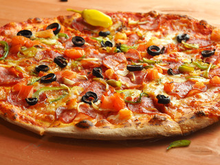 Hot pizza with tomatoes cheese and olives on wooden table
