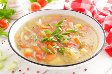 Vegetable soup. Healthy food, vegetarian dish. Vegetable soup with cabbage, potato, tomato, carrot, celery, pepper and green peas. Vegan diet menu. Top view