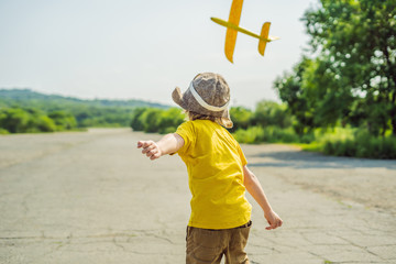 Happy kid playing with toy airplane against old runway background. Traveling with kids concept