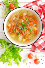 Vegetable soup. Healthy food, vegetarian dish. Vegetable soup with cabbage, potato, tomato, carrot, celery, pepper and green peas. Vegan diet menu. Top view