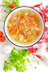Vegetable soup. Healthy food, vegetarian dish. Vegetable soup with cabbage, potato, tomato, carrot, celery, pepper and green peas. Vegan diet menu. Top view