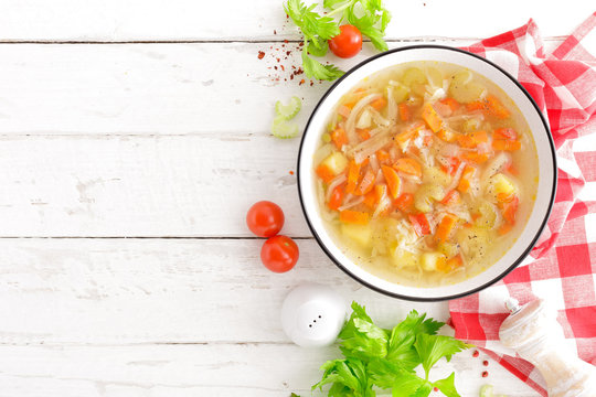 Vegetable soup. Healthy food, vegetarian dish. Vegetable soup with cabbage, potato, tomato, carrot, celery, pepper and green peas. Vegan diet menu. Top view