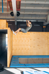 young active man climbing up on the wall of a gym during a workout. side view full length photo....
