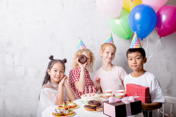 funny little girl looking though the cake while her friends are posing to the camera. closeup shot.