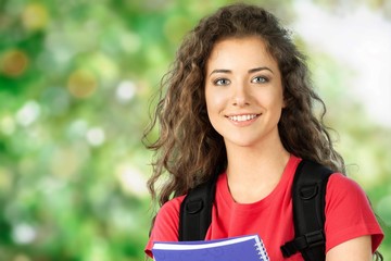 Fototapeta premium Portrait of a cute young student girl holding colorful notebook