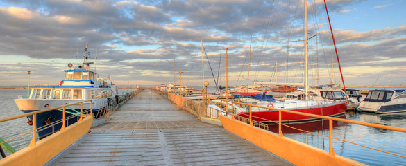 Pier and boats with yachts on the background of a beautiful sunset. Marina in the city of Odessa, Ukraine