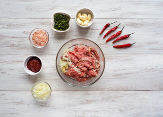 Minced meat and ingredients for cutlets are laid out on a wooden table. Preparation of delicious...