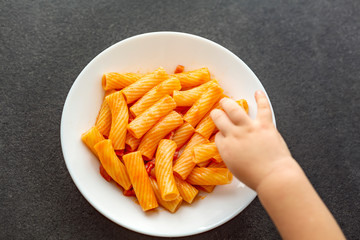 Little child eats fresh pasta with tomato sauce parmesan cheese