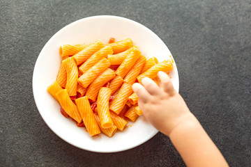 Little child eats fresh pasta with tomato sauce parmesan cheese