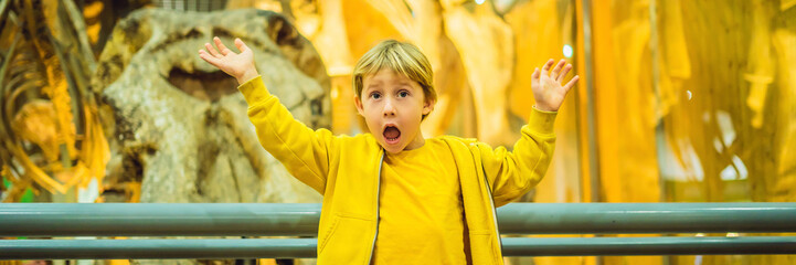 The Boy watching dinosaur skeleton in museum BANNER, LONG FORMAT