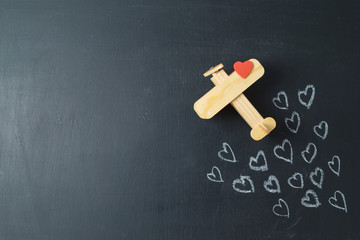 Valentines day concept with heart shapes and airplane toy over chalkboard background