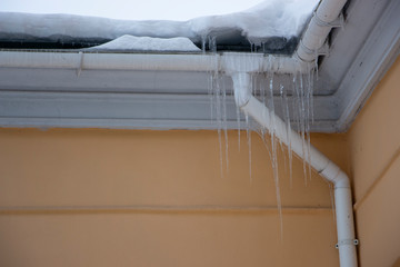 Icicles on the drainpipe and ditch. Incorrect installation of the drainage system, on which large...
