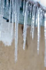 Icicles on an old, rusty, rural roof. Clay wall