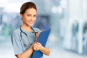 Attractive young female doctor with blurred hospital interior on