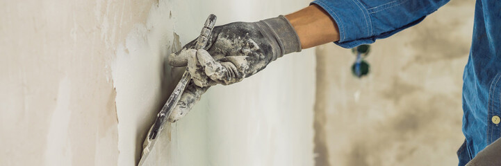 master is applying white putty on a wall and smearing by putty knife in a room of renovating house...