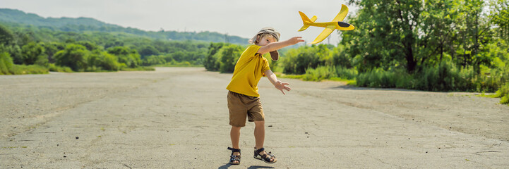Happy kid playing with toy airplane against old runway background. Traveling with kids concept BANNER, LONG FORMAT